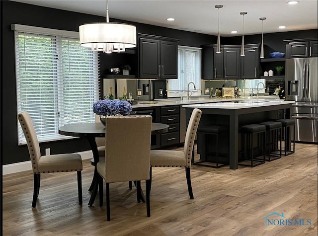 kitchen with a center island, stainless steel fridge, decorative light fixtures, and light hardwood / wood-style flooring