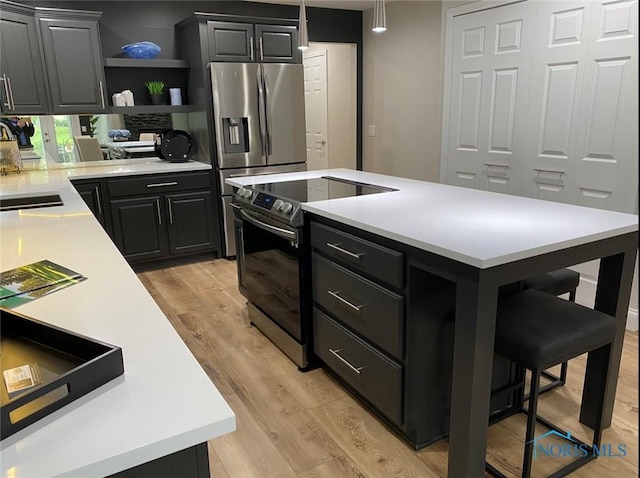 kitchen with stainless steel appliances, a kitchen bar, a kitchen island, and light wood-type flooring