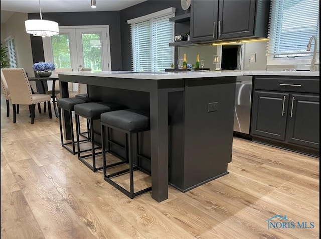 kitchen featuring sink, light hardwood / wood-style flooring, a kitchen bar, and decorative light fixtures