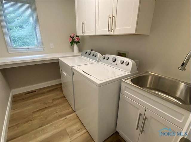 laundry room featuring cabinets, sink, washing machine and clothes dryer, and light wood-type flooring