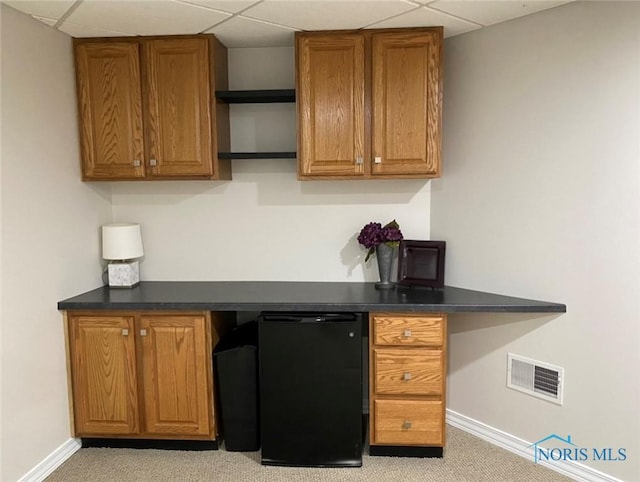 kitchen featuring light carpet, a paneled ceiling, and refrigerator