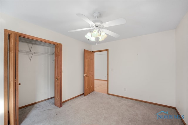 unfurnished bedroom featuring ceiling fan, light colored carpet, and a closet