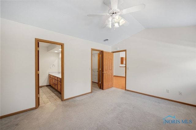 unfurnished bedroom featuring lofted ceiling, connected bathroom, a spacious closet, light colored carpet, and a closet