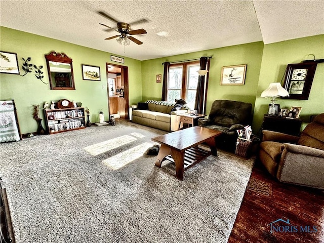 living room with dark colored carpet, a textured ceiling, and ceiling fan