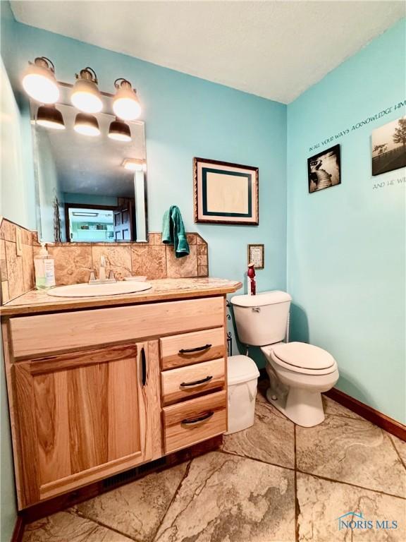 bathroom with vanity, decorative backsplash, and toilet