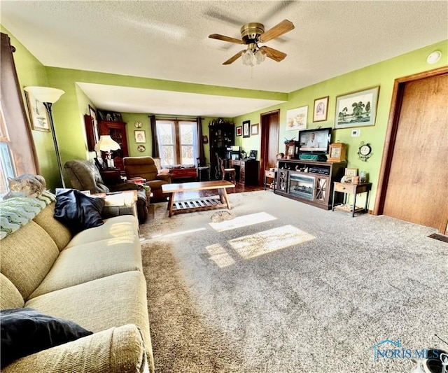 living room featuring ceiling fan, carpet floors, and a textured ceiling