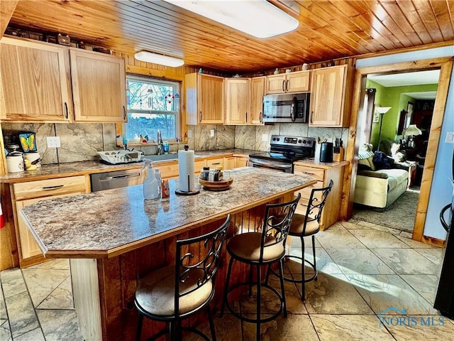 kitchen featuring a breakfast bar, decorative backsplash, a center island, stainless steel appliances, and light brown cabinets