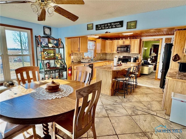 dining area featuring ceiling fan, sink, and a textured ceiling