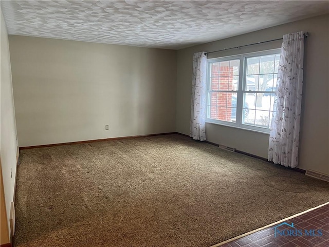 unfurnished room featuring a textured ceiling and dark carpet