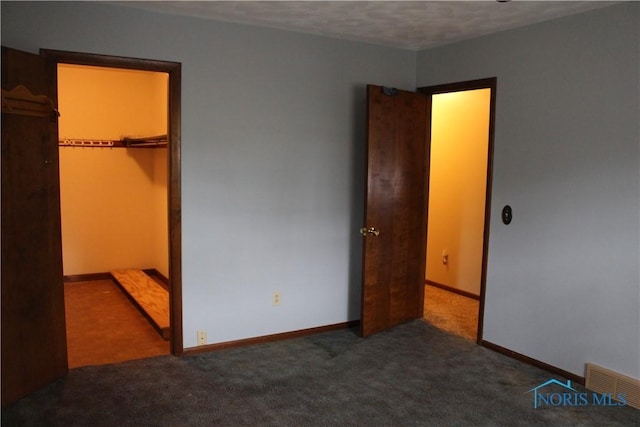 unfurnished bedroom with a spacious closet, carpet floors, and a closet