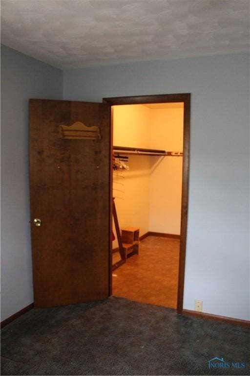 unfurnished bedroom featuring a spacious closet, carpet floors, and a closet