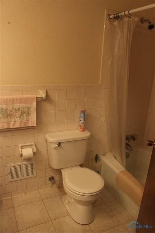 bathroom featuring tile walls, shower / bathtub combination with curtain, tile patterned floors, and toilet