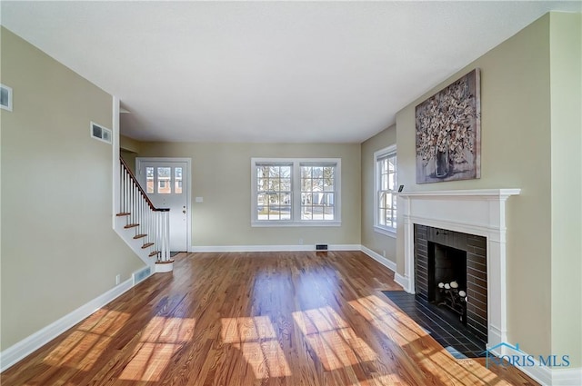 unfurnished living room featuring a brick fireplace and dark hardwood / wood-style floors