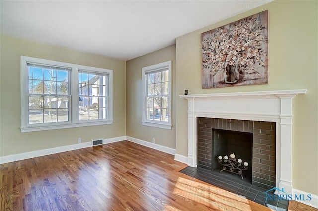 unfurnished living room featuring hardwood / wood-style floors and a brick fireplace