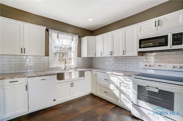 kitchen with sink, white appliances, light stone countertops, and white cabinets