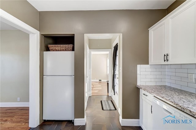 kitchen featuring light stone counters, dark hardwood / wood-style floors, white cabinets, white appliances, and backsplash