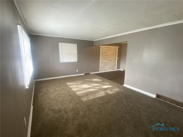 empty room featuring ornamental molding and dark carpet