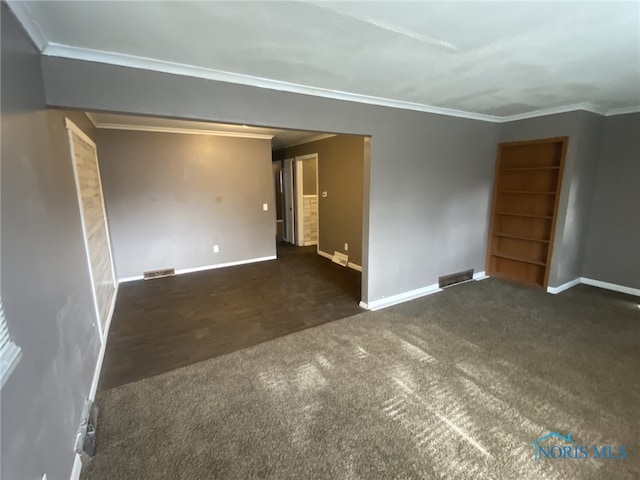 empty room featuring crown molding and dark colored carpet