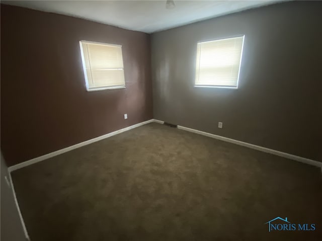 spare room with dark colored carpet