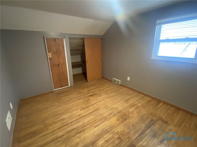 bonus room with vaulted ceiling and light wood-type flooring