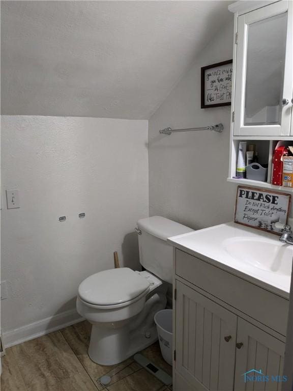 bathroom with vanity, hardwood / wood-style flooring, vaulted ceiling, and toilet