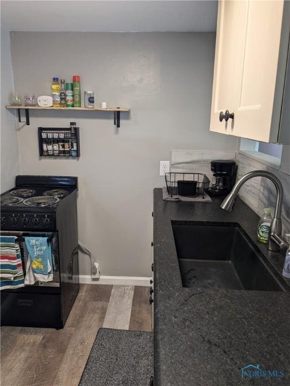 kitchen with sink, dark hardwood / wood-style floors, black stove, and white cabinets