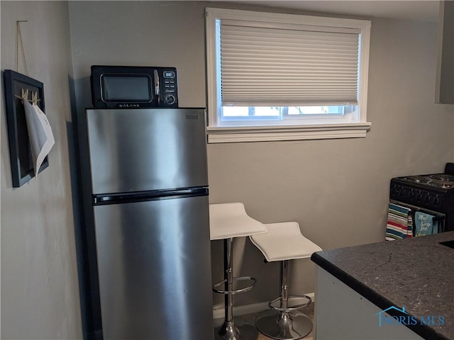 kitchen featuring stainless steel refrigerator and black stove