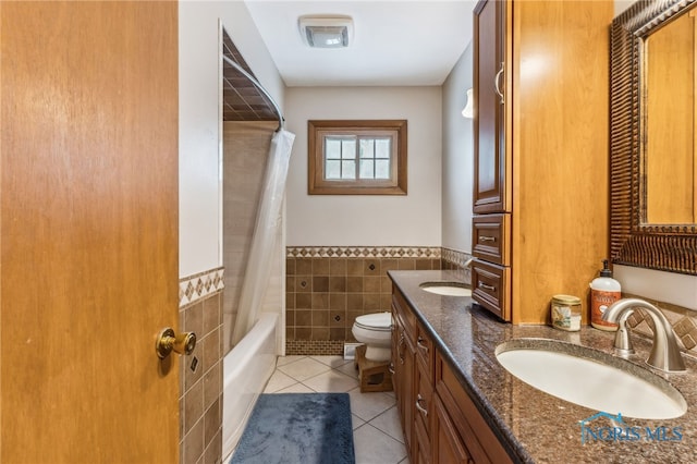 full bathroom with shower / tub combo with curtain, tile walls, tile patterned flooring, vanity, and toilet