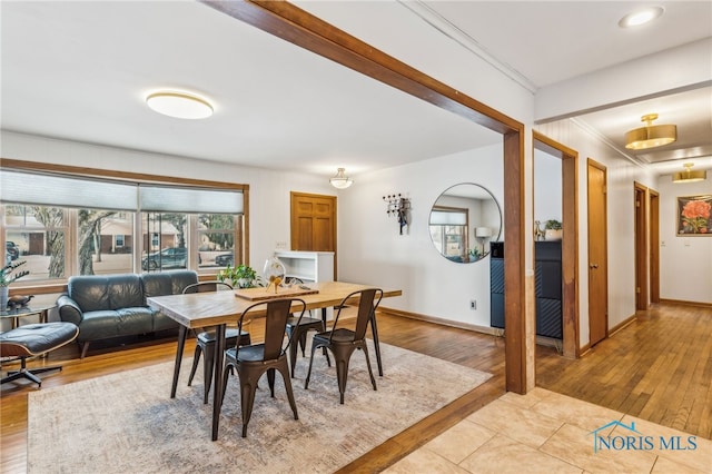 dining room with ornamental molding and light hardwood / wood-style flooring