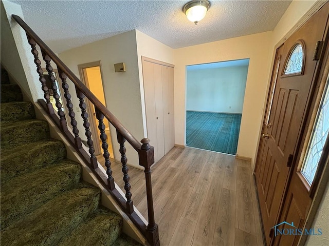 entrance foyer featuring a textured ceiling and light wood-type flooring