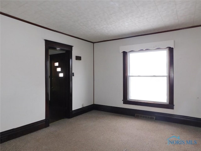 empty room featuring crown molding and light colored carpet