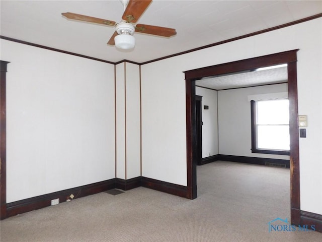 unfurnished room featuring light carpet, crown molding, and ceiling fan