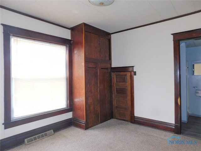 unfurnished bedroom featuring crown molding and light carpet