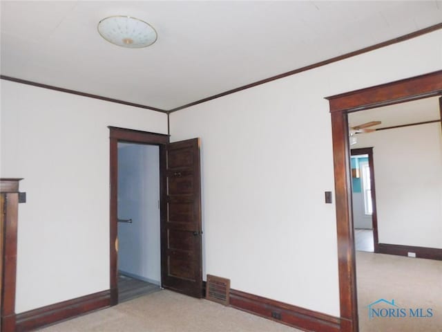 unfurnished room with crown molding and light carpet