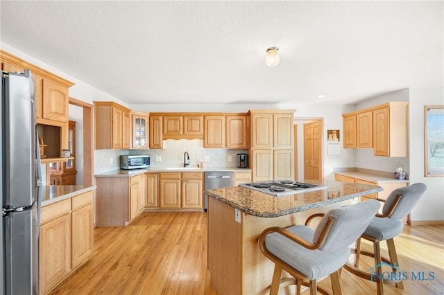 kitchen featuring sink, light hardwood / wood-style flooring, a breakfast bar, stainless steel appliances, and a kitchen island