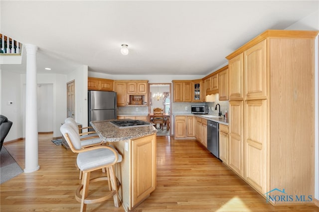 kitchen featuring a breakfast bar, sink, a center island, stainless steel appliances, and decorative columns