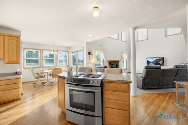 kitchen featuring a textured ceiling, light brown cabinets, light hardwood / wood-style flooring, electric range, and a fireplace