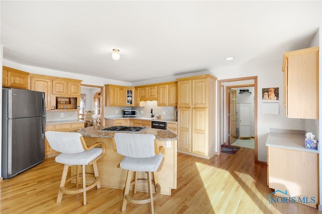 kitchen featuring a kitchen bar, a center island, light wood-type flooring, stainless steel appliances, and backsplash