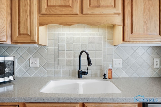 kitchen with sink, backsplash, and light stone countertops