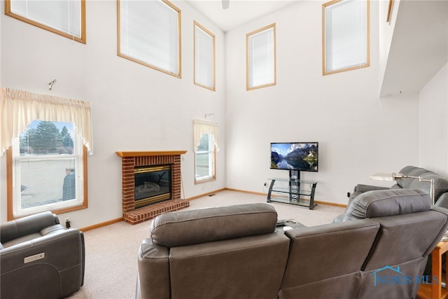 carpeted living room featuring a towering ceiling and a fireplace