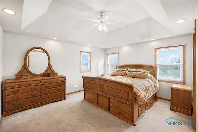 carpeted bedroom with a raised ceiling and ceiling fan