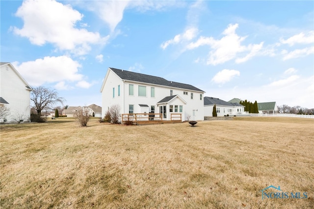 rear view of house with a wooden deck and a lawn