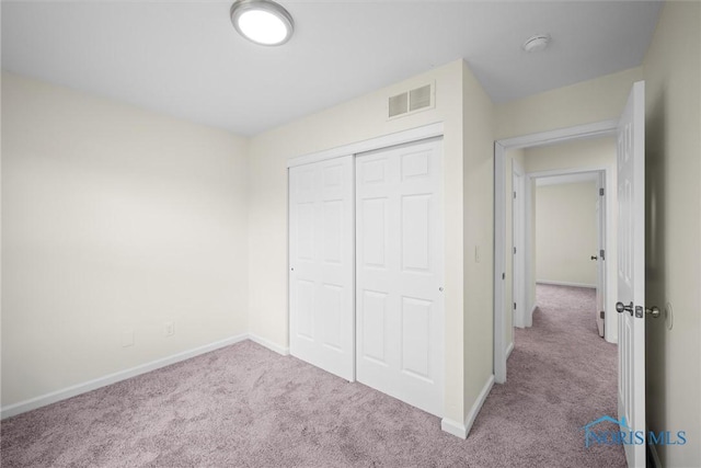 unfurnished bedroom with light colored carpet and a closet