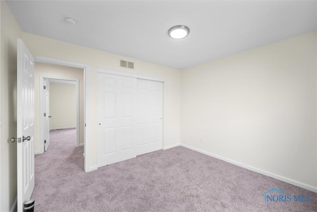 unfurnished bedroom featuring light carpet and a closet