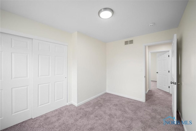 unfurnished bedroom featuring light colored carpet and a closet