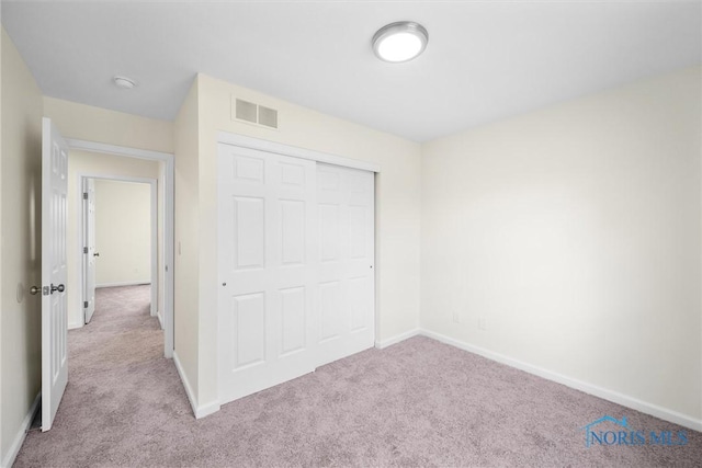 unfurnished bedroom with light colored carpet and a closet