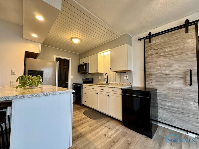 kitchen featuring light hardwood / wood-style flooring, white cabinets, light stone counters, and black appliances