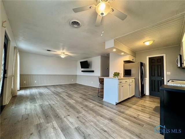 kitchen featuring stainless steel appliances, white cabinetry, a breakfast bar, and light hardwood / wood-style flooring