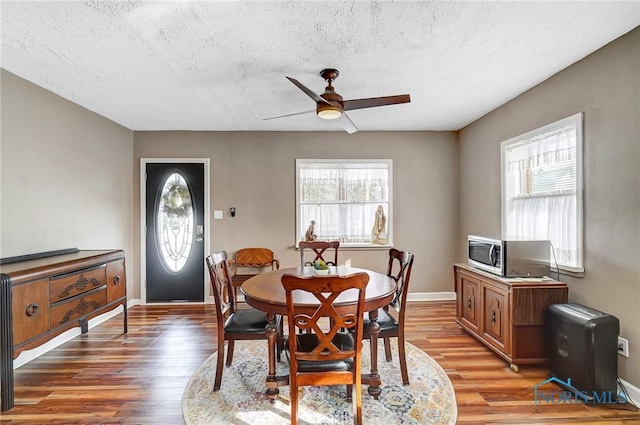 dining space with hardwood / wood-style floors, a healthy amount of sunlight, ceiling fan, and a textured ceiling