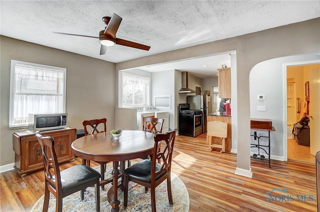 dining area with light hardwood / wood-style flooring, ceiling fan, separate washer and dryer, and a textured ceiling